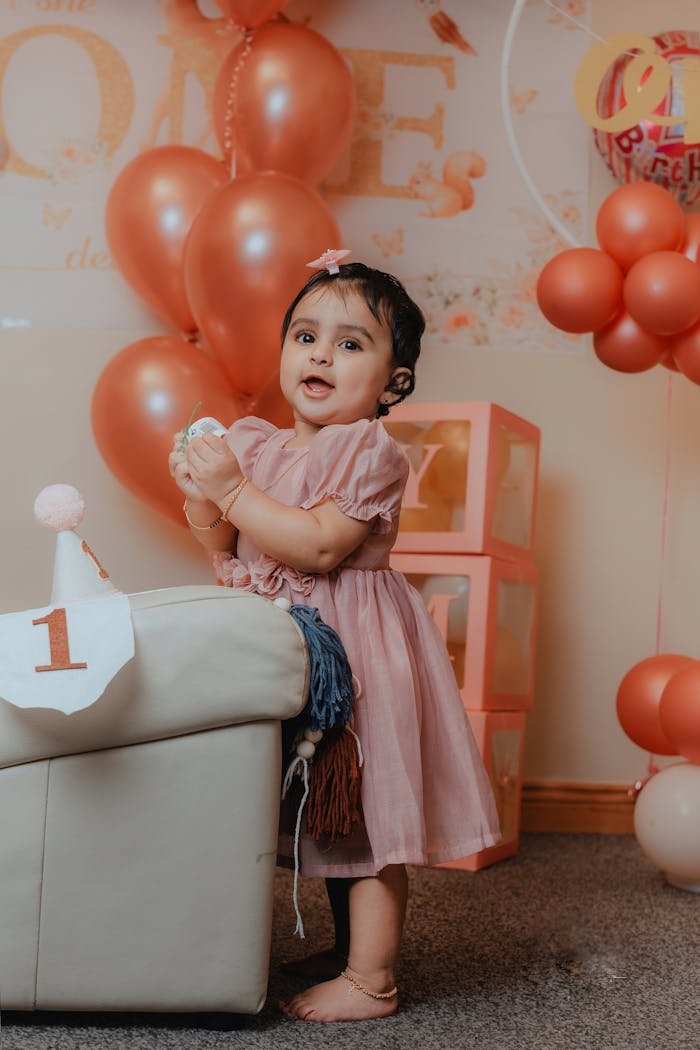 creative-03 Charming photo of a little girl in a pink dress enjoying her first birthday with balloons.
