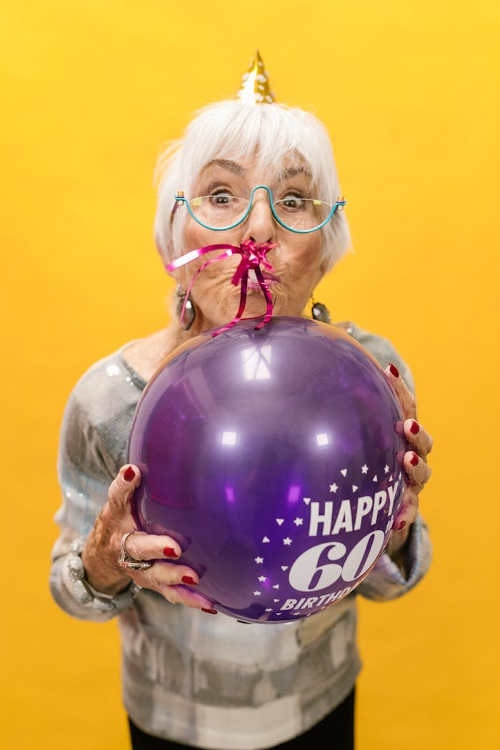 Joyful senior woman celebrating her 60th birthday with a decorative balloon.